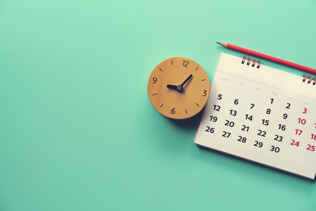 close up of calendar and alarm clock on the green table, planning for business meeting or travel planning concept