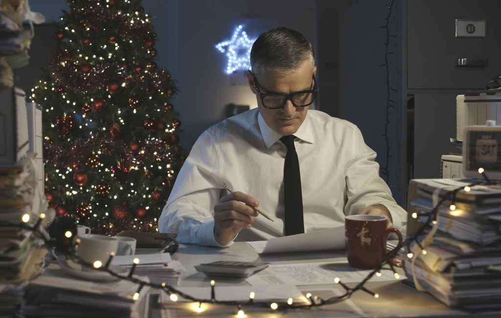 Sad businessman working on Christmas Day, he is surrounded by piles of paperwork