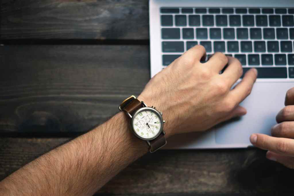 man checking time while working on computer