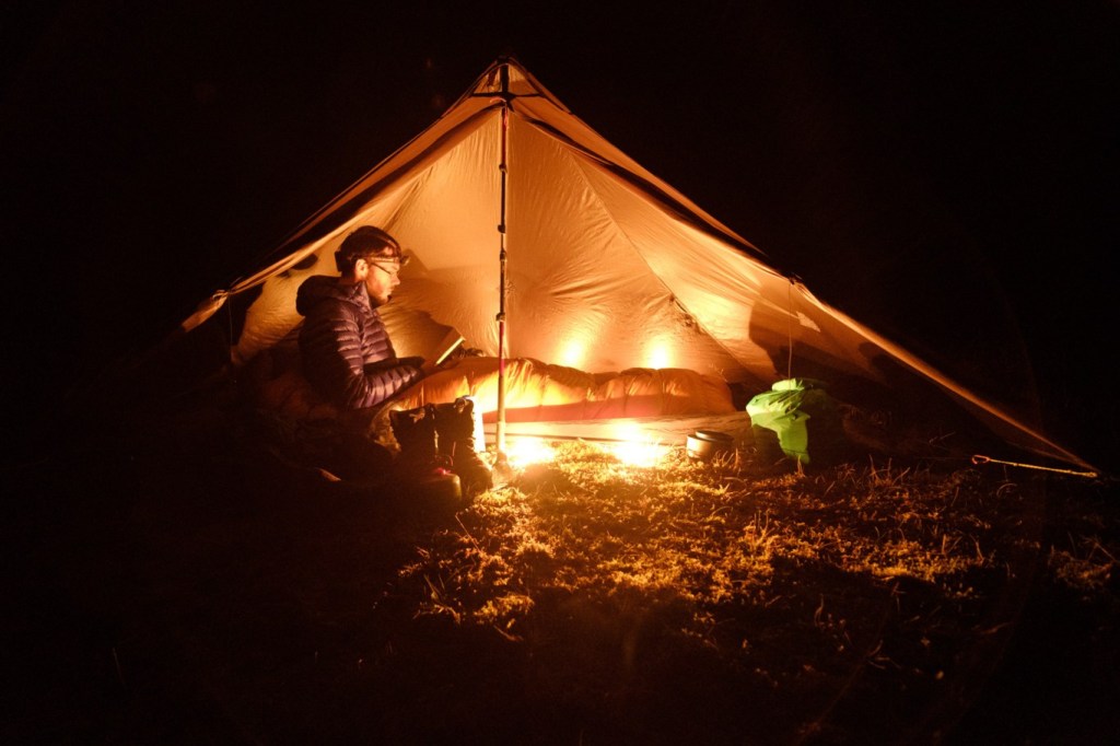 Man reading at night with headlamp while camping in the wild