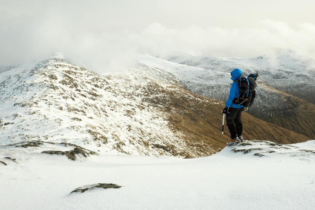 Hiker looks out on snowy mountains