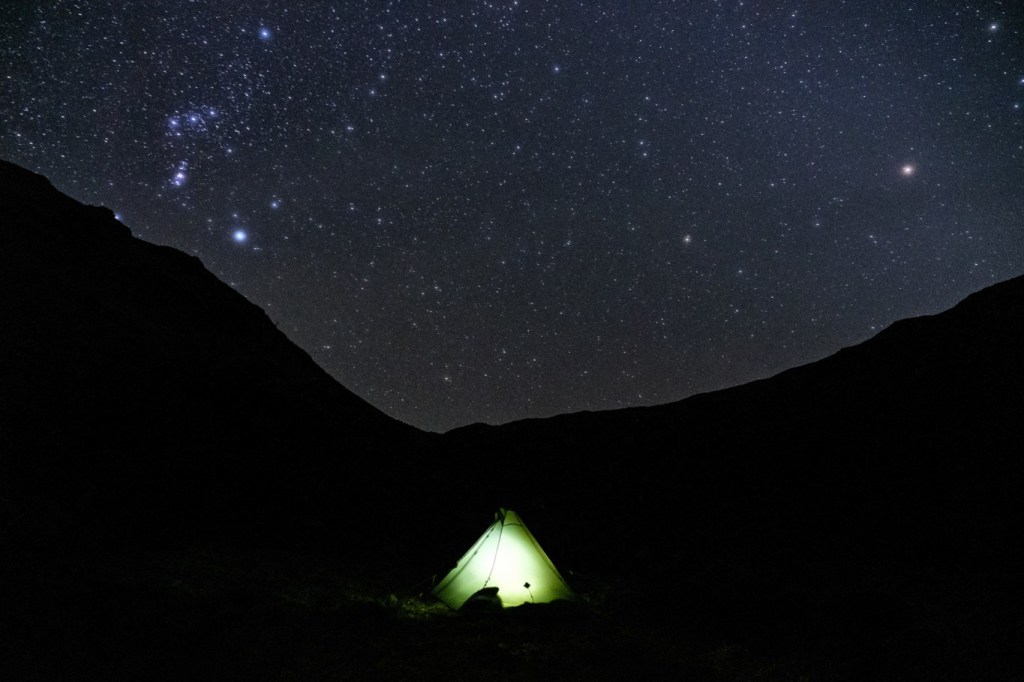 illuminated tent under a starry night sky