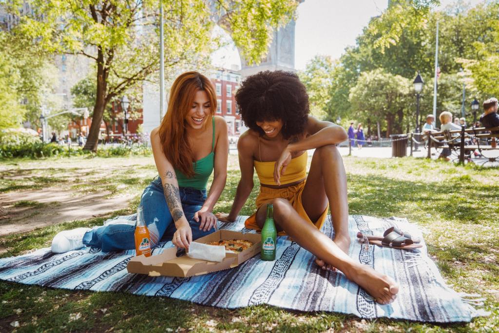 two women enjoying pizza in a park 