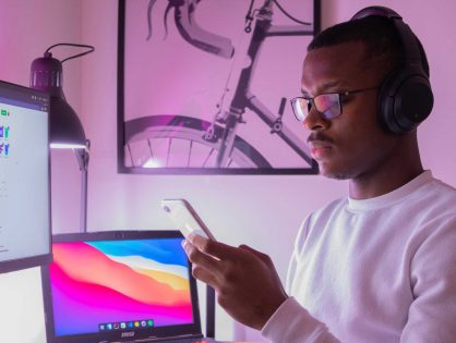 man looking at phone with mac in background