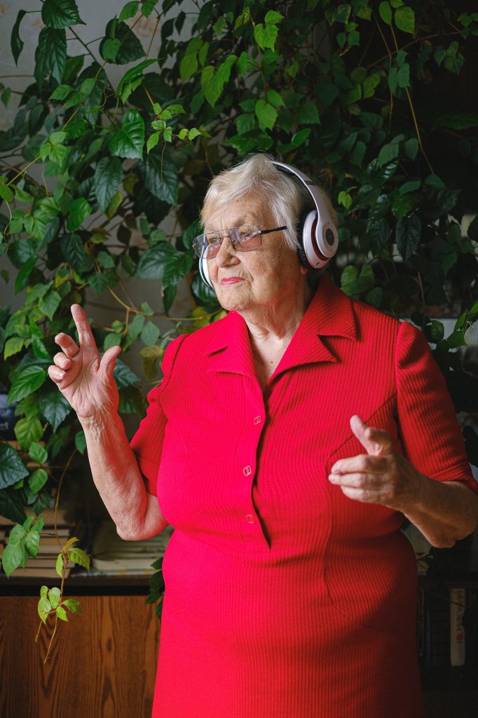 elderly woman listening to music with headphones and dancing