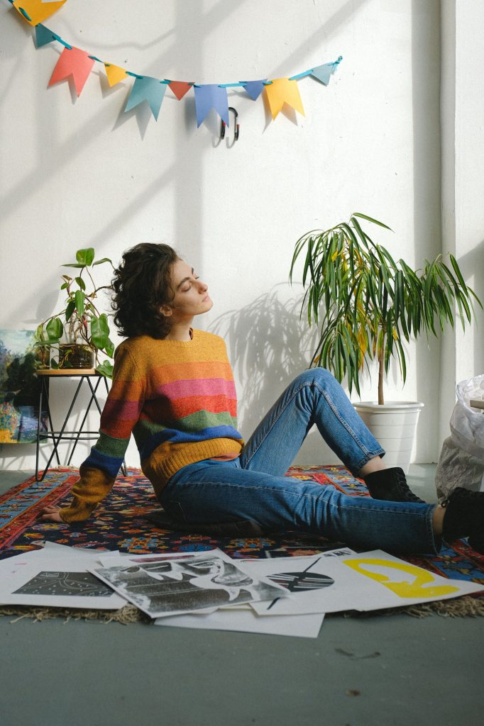 woman sittinf on the floor of apartment surrounded by drawings