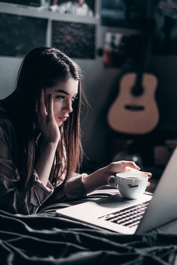 woman waking up with coffee and laptop in bed