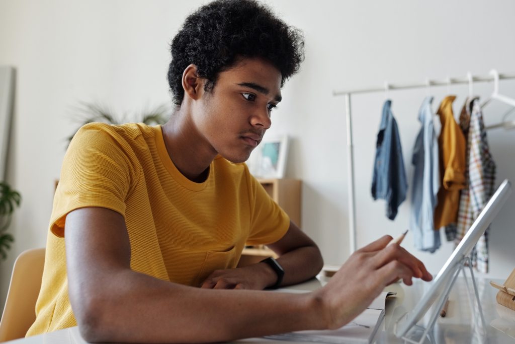 Teen boy studies using tablet ipad device