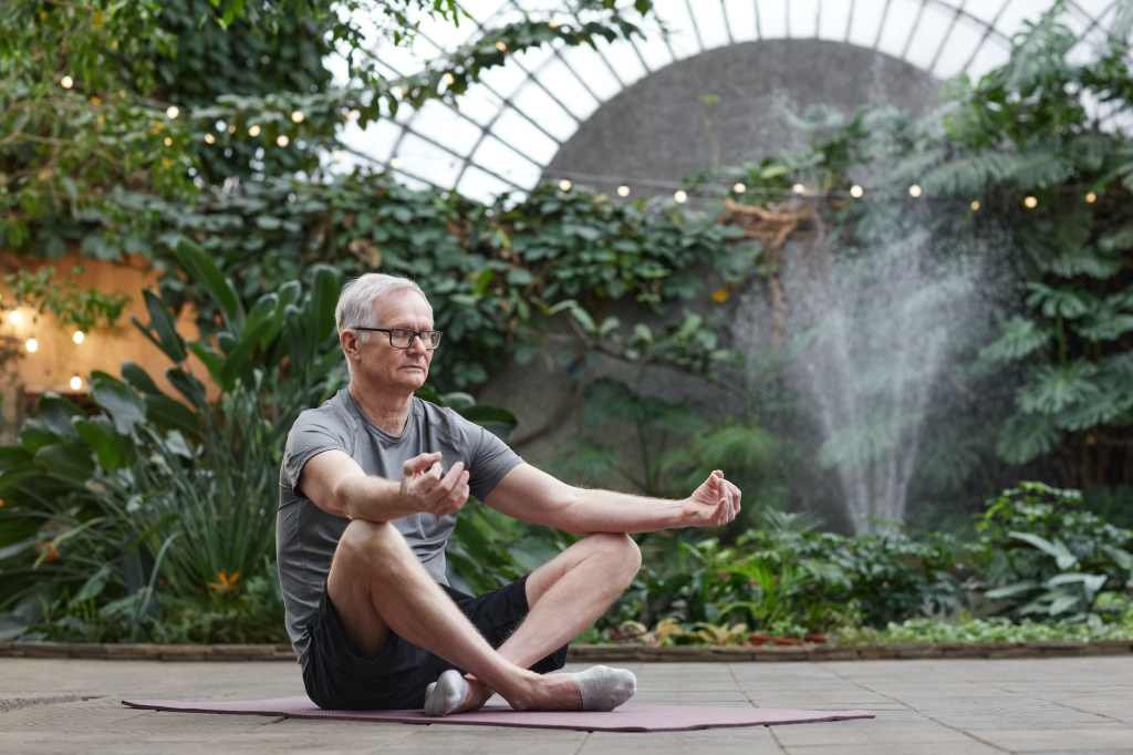 middle-aged man meditating in garden