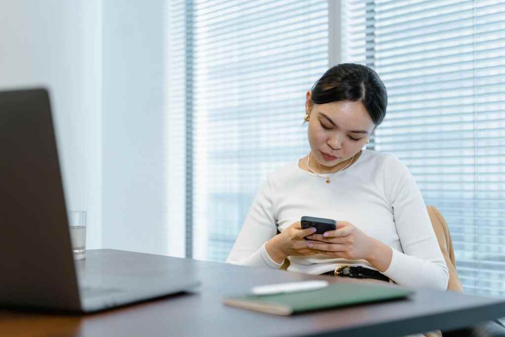 woman scrolling phone while at work in the office