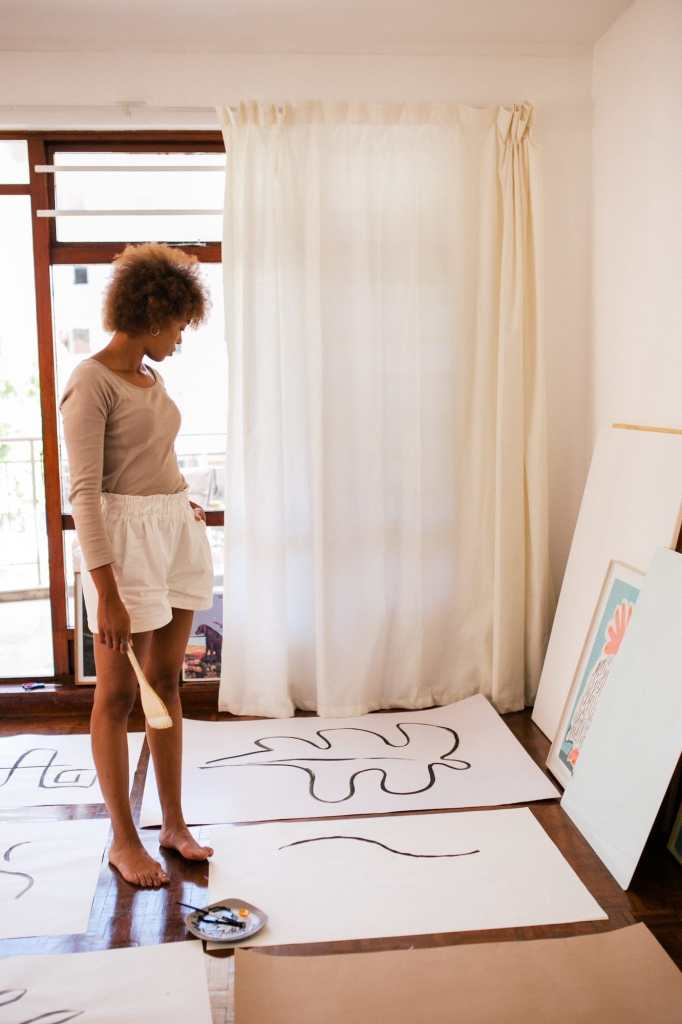 female artist contemplating her paintings in apartment